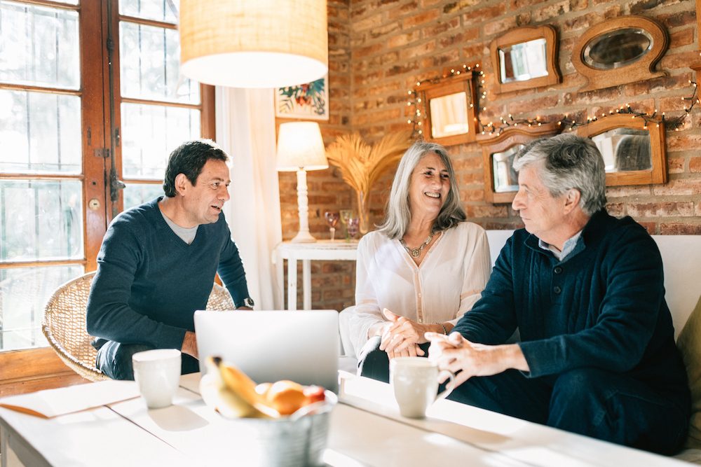 Trois copropriétaires discutant autour d'un ordinateur portable dans un intérieur chaleureux