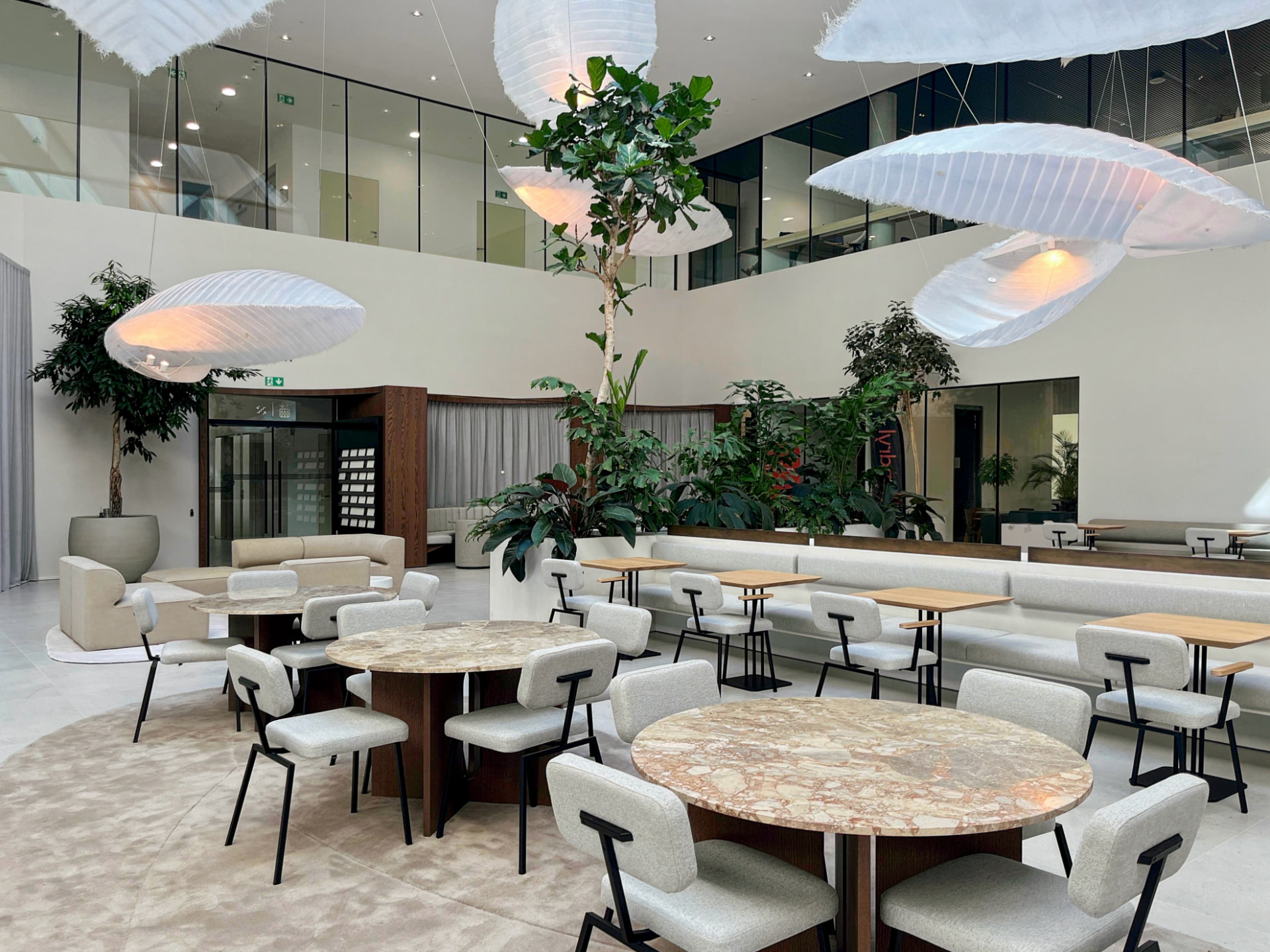 Lounge d'affaires contemporain avec plantes, assises claires et tables, dans un centre de bureaux flexibles près de la gare du Midi à Saint-Gilles