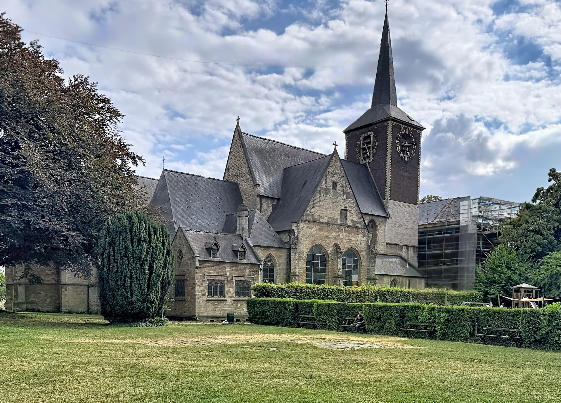 Église Saint-Denis de Forest, ancienne abbaye au clocher pointu entourée de verdure