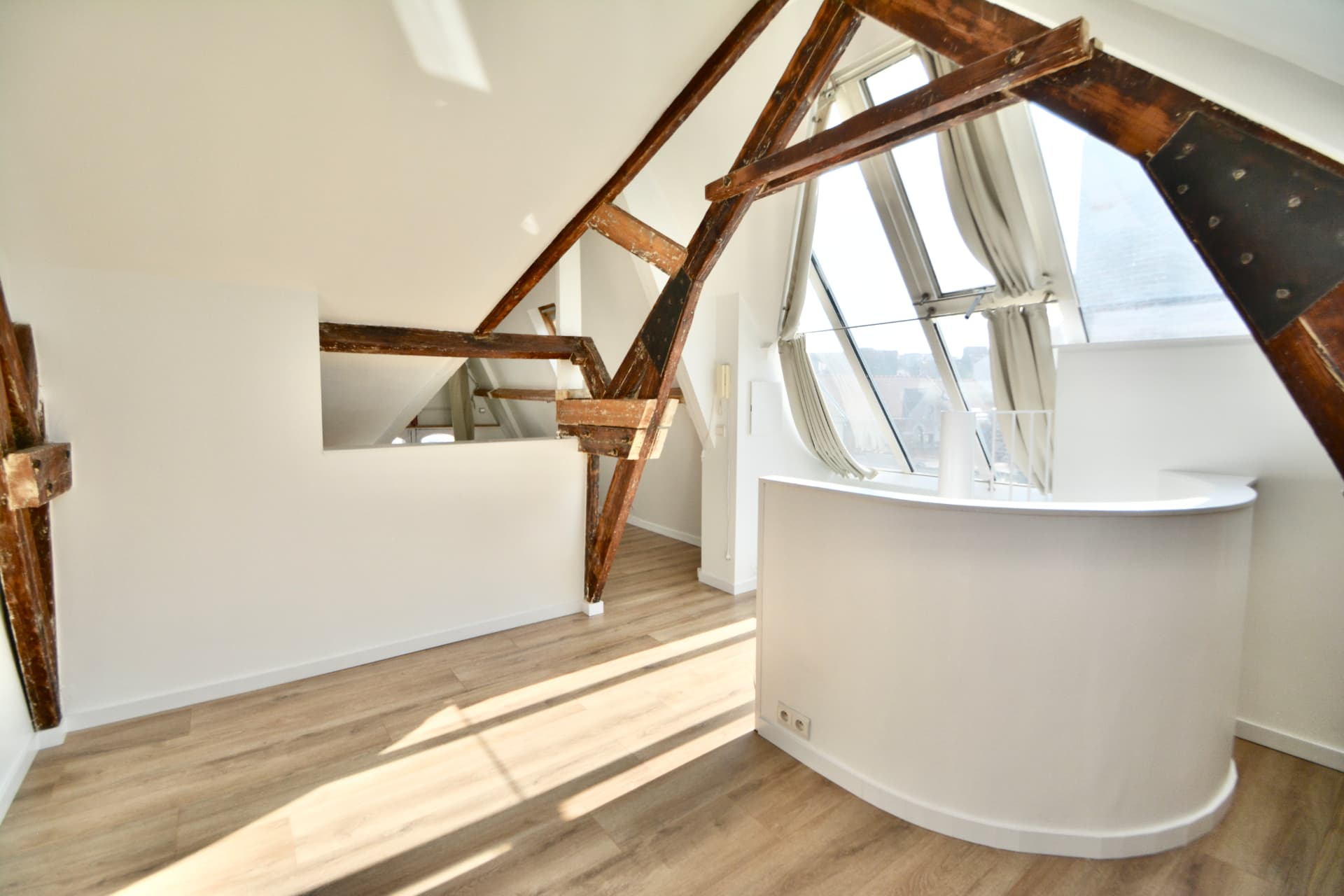 Duplex bruxellois lumineux sous charpente en bois apparente, avec grande verrière et parquet clair