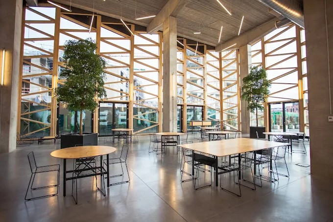 Intérieur du site Greenbizz à Laeken : atrium vitré, arbres et grandes tables