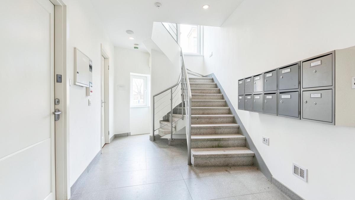 Hall d'entrée soigné d'un immeuble à appartements avec escalier et boîtes aux lettres