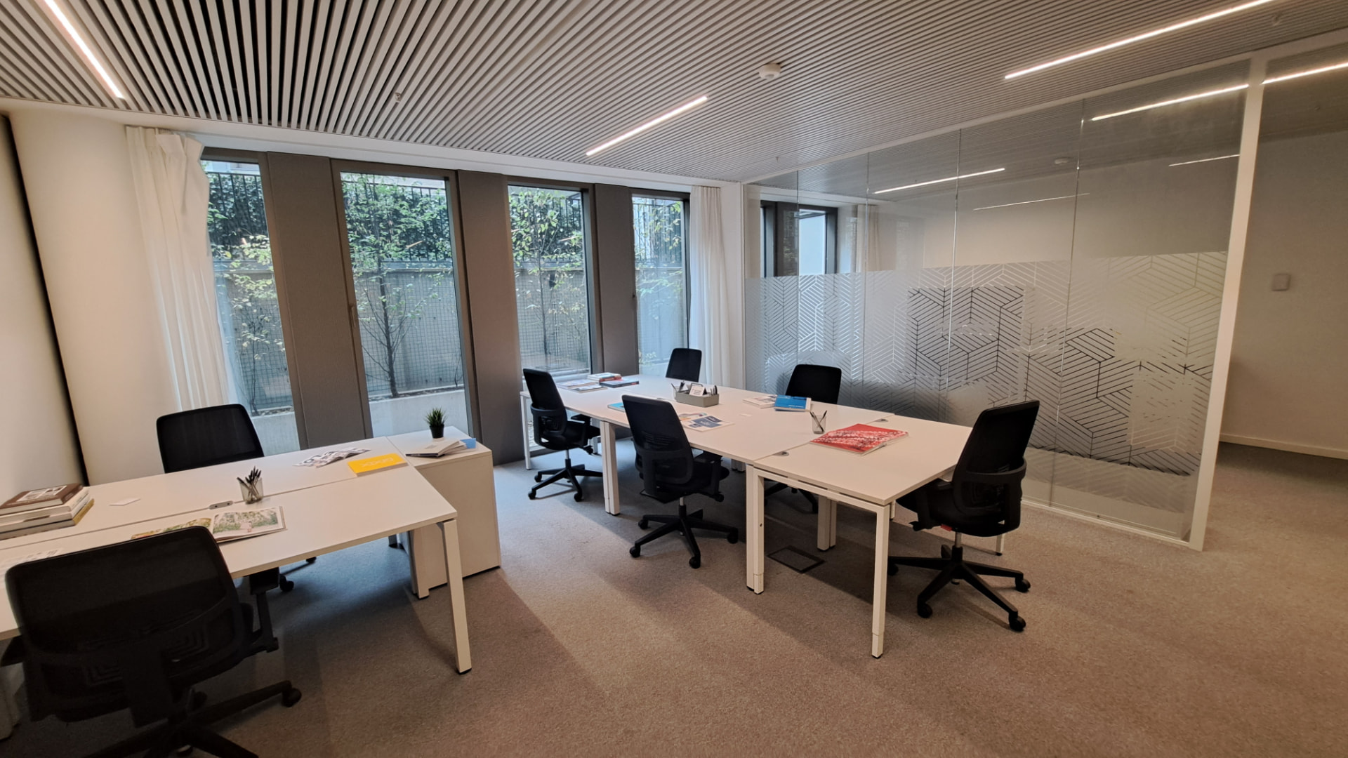 Bureau privé lumineux avec postes de travail blancs, grandes fenêtres et cloison vitrée, dans un immeuble récent du quartier du canal à Anderlecht