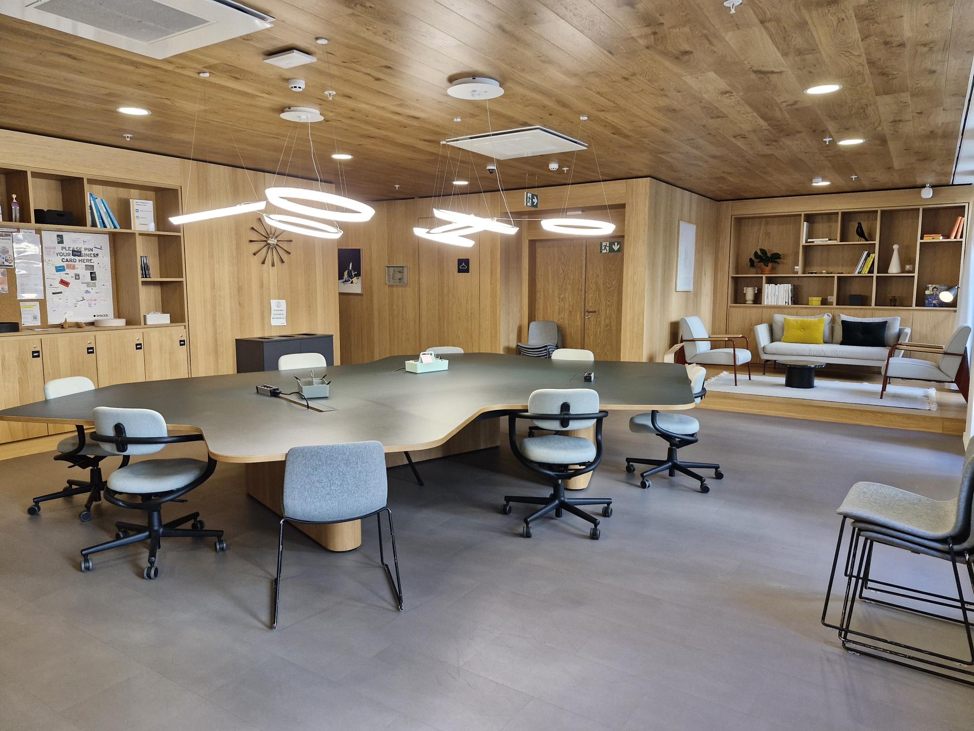 Salle de réunion professionnelle avec longue table en bois, fauteuils et boiseries, dans un bureau flexible du quartier Louise à Ixelles