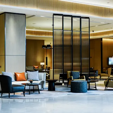 Espace d'accueil contemporain avec canapés et fauteuils, cloison ambrée et boiseries, dans un centre de bureaux flexibles du quartier européen à Etterbeek